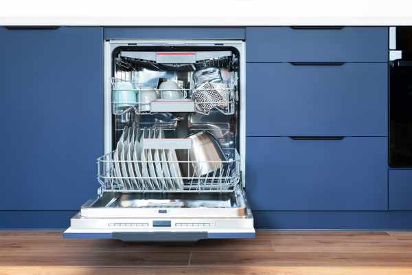 iStock Credit: simpson33 An open dishwasher against blue cabinetry